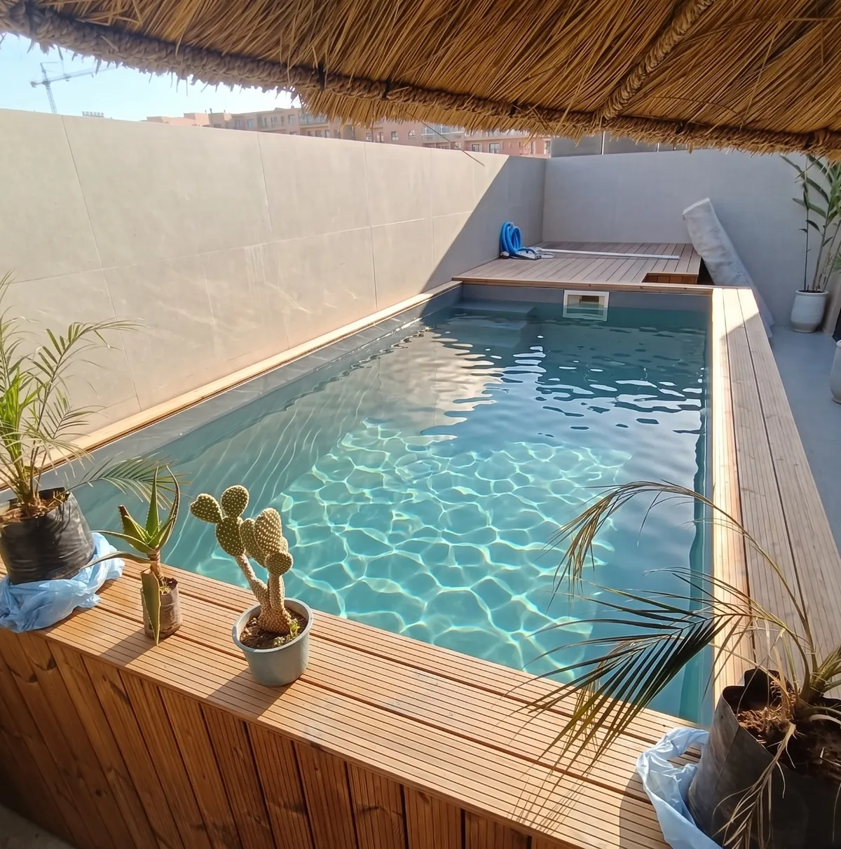 Piscine hors-sol en polyester achevée, structure autoportante habillée de bois sur un toit-terrasse